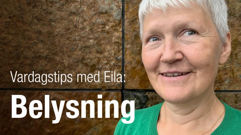 Eila har kort, grått hår och står framför en rostbrun vägg. Hon ser glad ut.