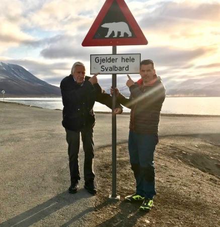 Torsten och Jonas står och håller i en varningskylt för isbjörnar på Svalbard