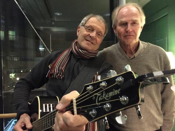 De två upphovsmakarna till julhiten Mer jul står redo att sjunga för Insyns lyssnare. Thomas håller i en gitarr och Anders står brevid. De är båda klädda i bruna tröjor.