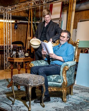 Roger sitter i en stol med manus i hösta hugg och Rasmus står och blickar ned i pappersbunten.