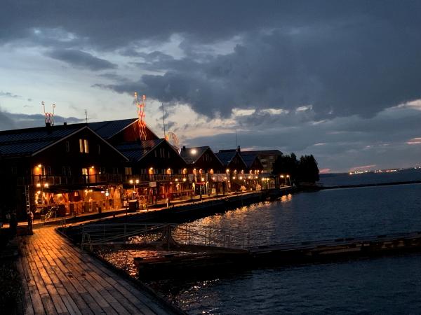 Norrbottensteatern fotad en sen höstkväll med mörk dramatisk himmel och många lampor framför de röda magasinsbyggnaderna.