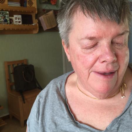 Anita har kort grått hår och en grå tröja. Hon ser glad ut på bilden.