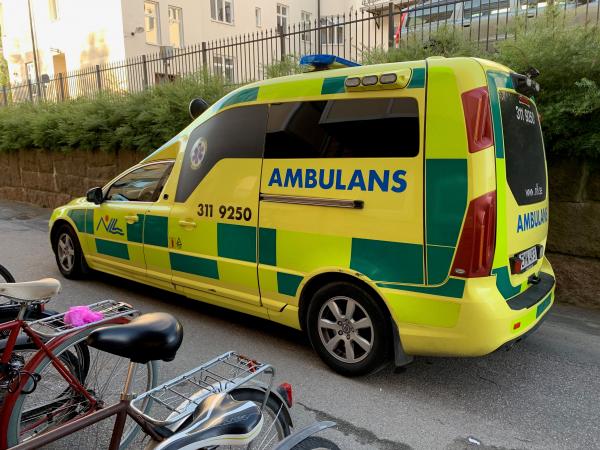 En gul och grön ambulans står utanför ett bostadshus