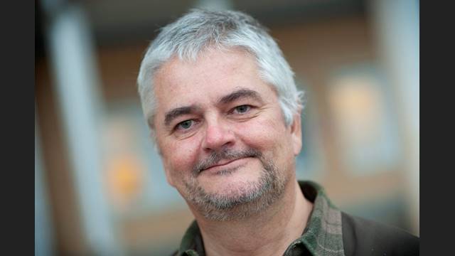 Anders har grått kort hår och ser glad ut på porträttbilden