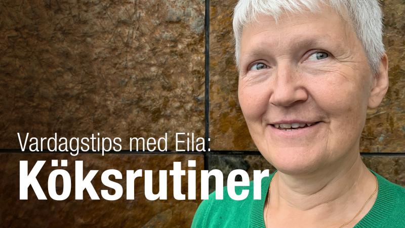 Eila har kortklippt, grått hår och bruna ögon. Hon har en grön topp och står vid en brun stenvägg.