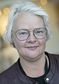 Åsa har blont, kort hår och bär glasögon.