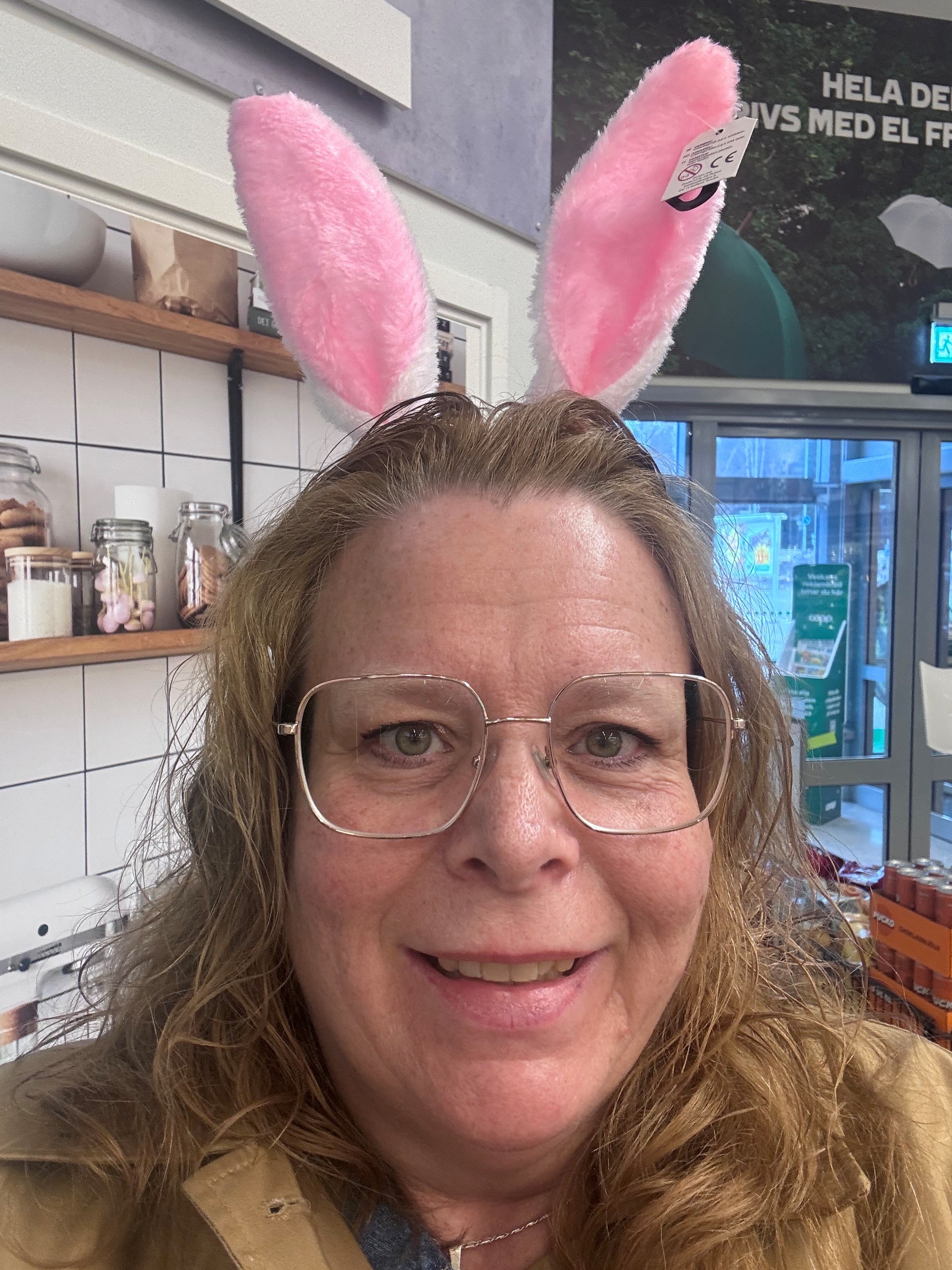 Taltidningsredaktören Eva Marie ser glad ut. Hon har ett par rosa-vita kaninöron på huvudet. Hon har mörkt, långt hår. Bär glasögon med guldfärgad, tunn båge och har gröna ögon. Hennes kappa är guldbrun och hon står på en livsmedelaffär.