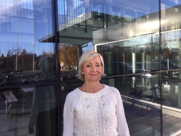 Utvecklingsdirektör Lisbeth Löpare Johansson speglas i Regionhusets fönster. Hon är blond, kortklippt och har en vit tröja på sig.